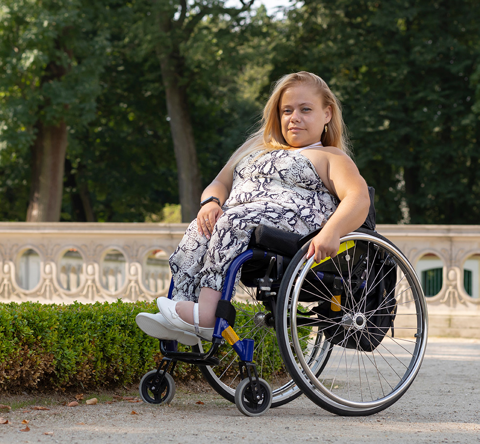 Young woman in a beautiful sundress and white shoes using a wheelchair.