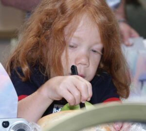 Adorable girl with Kniest. She has red hair and is concentrating on coloring.